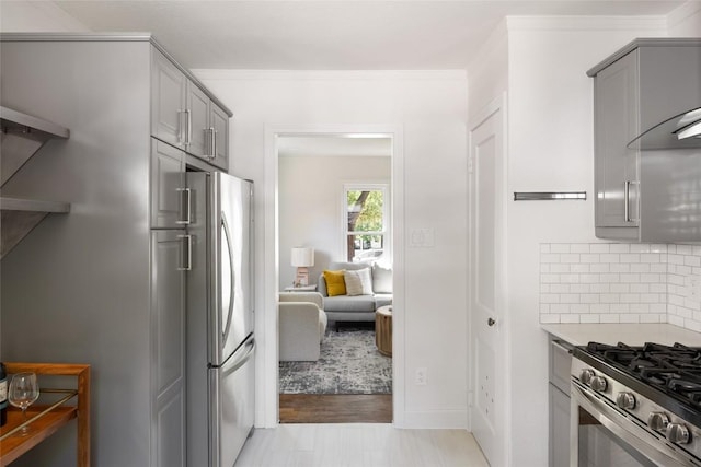 5306 Harmon Ave, Austin, TX 78751 - kitchen with appliances with stainless steel finishes, gray cabinets, tasteful backsplash, light countertops, and ornamental molding