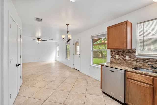 18109 Canopy Ln, Manor, TX 78653 - kitchen with stainless steel dishwasher, a sink, light tile patterned floors, a chandelier, and brown cabinets