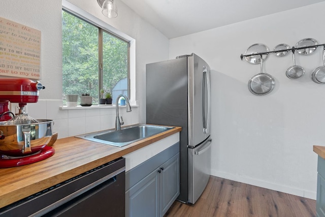 5206 Ledesma Rd, Austin, TX 78721 - kitchen with black dishwasher, a sink, backsplash, dark wood-style flooring, and butcher block countertops