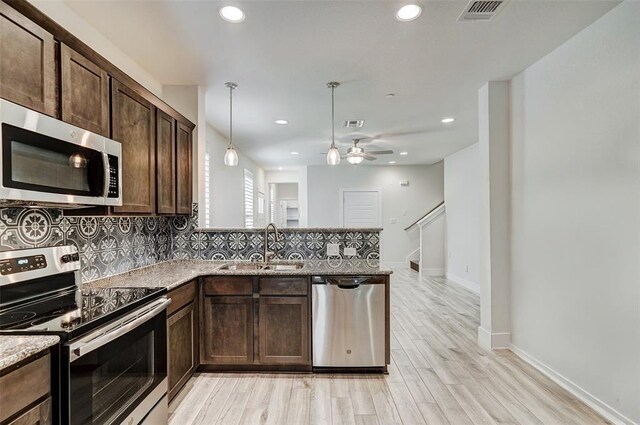1801 Roseburg Dr Unit 29, Austin, TX 78754 - kitchen with stainless steel appliances, a sink, dark brown cabinets, a peninsula, and decorative backsplash