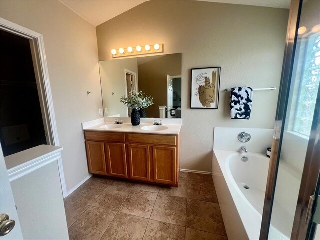 144 Sampson, Kyle, TX 78640 - bathroom featuring lofted ceiling, double vanity, a bath, baseboards, and tile patterned floors