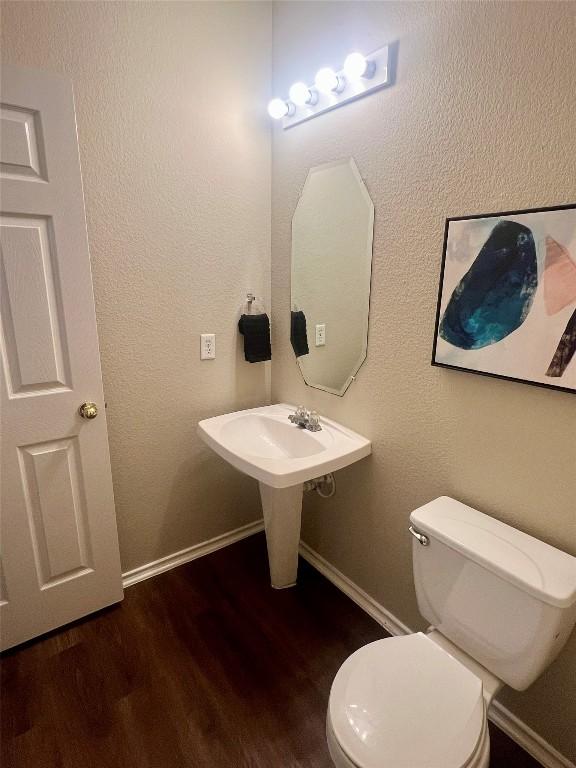 144 Sampson, Kyle, TX 78640 - bathroom featuring wood finished floors, toilet, and baseboards