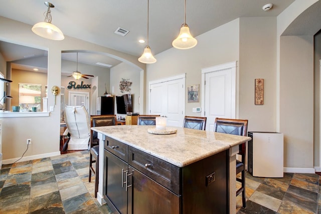 3808 Mattie St, Austin, TX 78723 - kitchen with a breakfast bar, dark stone finish floors, ceiling fan, arched walkways, and baseboards