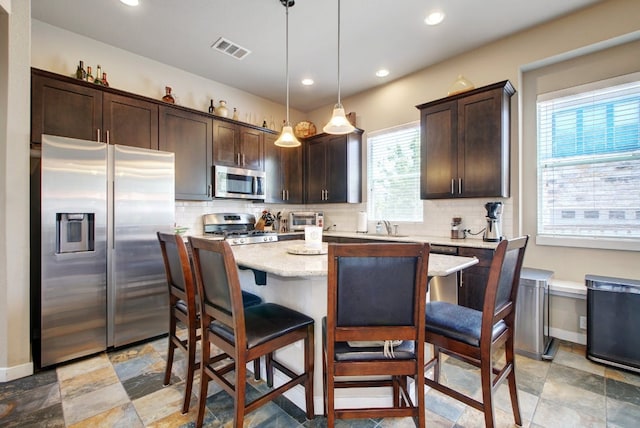 3808 Mattie St, Austin, TX 78723 - kitchen featuring appliances with stainless steel finishes, dark brown cabinets, tasteful backsplash, a center island, and recessed lighting