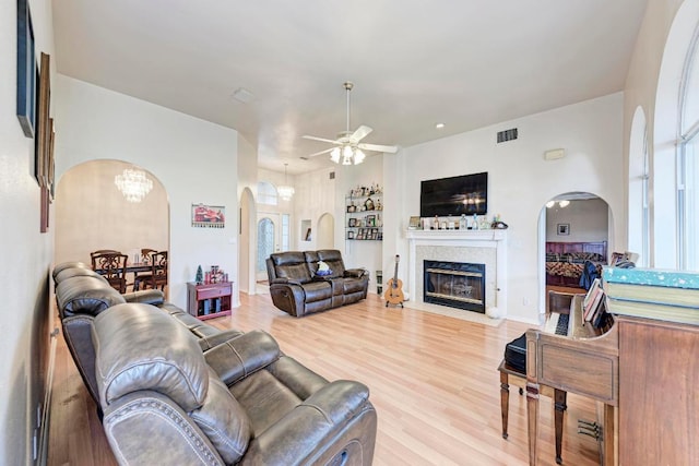 1610 Meadow Ln, Lockhart, TX 78644 - living room with arched walkways, a ceiling fan, a fireplace with flush hearth, light wood-style floors, and a chandelier