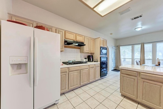 1610 Meadow Ln, Lockhart, TX 78644 - kitchen featuring black appliances, under cabinet range hood, light brown cabinetry, a warming drawer, and decorative backsplash