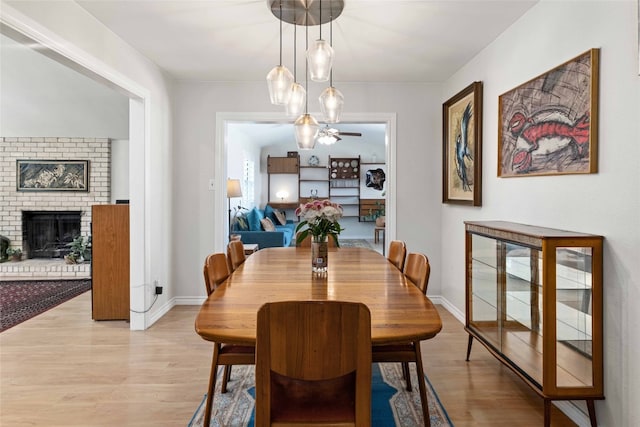 6903 Moonmont Dr, Austin, TX 78745 - dining space featuring light wood-style flooring, a brick fireplace, ceiling fan, and baseboards