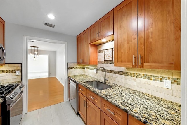 6903 Moonmont Dr, Austin, TX 78745 - kitchen featuring stainless steel appliances, a sink, light stone countertops, tasteful backsplash, and brown cabinetry