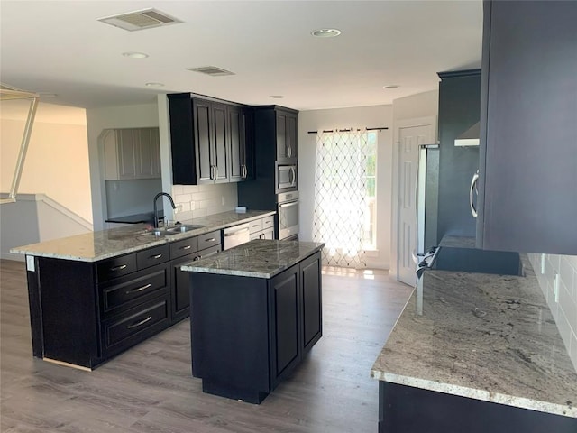 4102 Glendale Ln, Lago Vista, TX 78645 - kitchen with dark cabinetry, stainless steel appliances, decorative backsplash, light wood-type flooring, and recessed lighting