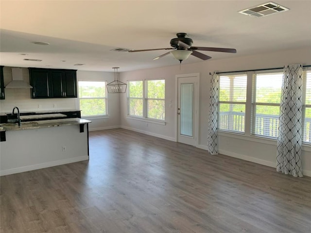 4102 Glendale Ln, Lago Vista, TX 78645 - kitchen with wall chimney range hood, ceiling fan, wood finished floors, decorative backsplash, and light stone counters