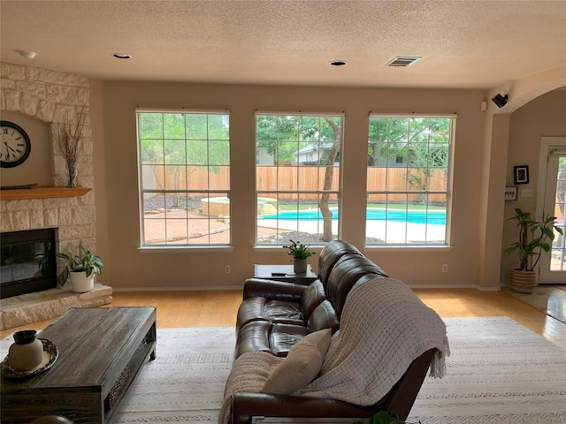 1813 Country Squire Dr, Cedar Park, TX 78613 - living area featuring wood finished floors, healthy amount of natural light, a textured ceiling, a stone fireplace, and baseboards
