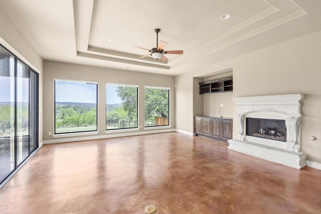 25036 River Rd, Spicewood, TX 78669 - unfurnished living room featuring a tray ceiling, concrete flooring, and plenty of natural light