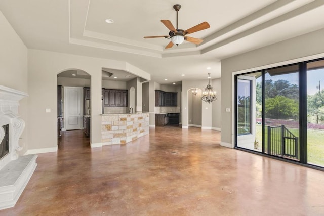 25036 River Rd, Spicewood, TX 78669 - unfurnished living room with a fireplace, a tray ceiling, finished concrete floors, a ceiling fan, and recessed lighting