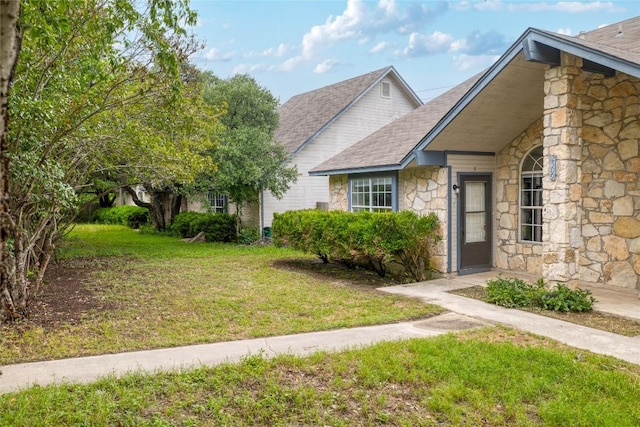 2509 Riddle Rd, Austin, TX 78748 - view of front of home featuring stone siding, a front yard, and a shingled roof