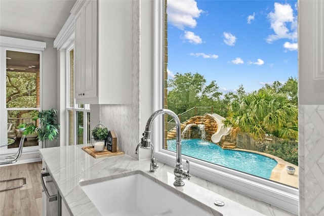 405 Mirafield Ln, Austin, TX 78737 - kitchen view of light stone countertops, white cabinetry, and a sink