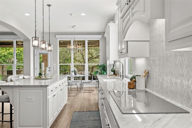 405 Mirafield Ln, Austin, TX 78737 - kitchen with a sink, a breakfast bar area, white cabinets, arched walkways, and pendant lighting
