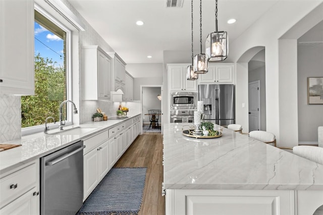 405 Mirafield Ln, Austin, TX 78737 - kitchen featuring appliances with stainless steel finishes, a sink, a spacious island, light stone counters, and tasteful backsplash