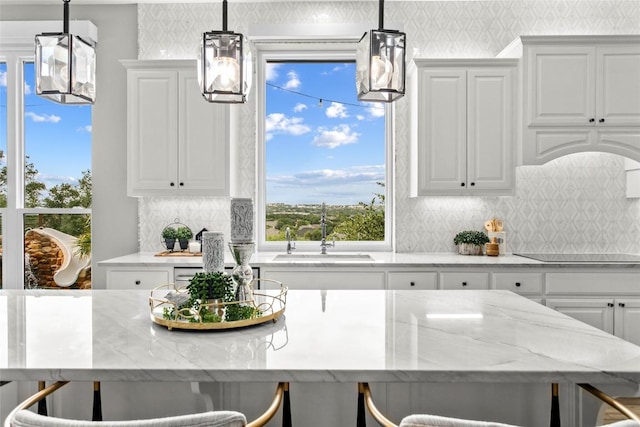 405 Mirafield Ln, Austin, TX 78737 - kitchen featuring a sink, wallpapered walls, light stone countertops, white cabinets, and backsplash