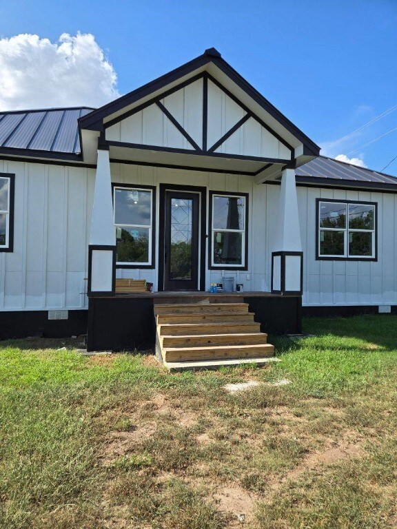 1525 Waco St, Gonzales, TX 78629 - back of house with board and batten siding, a lawn, covered porch, and a metal roof