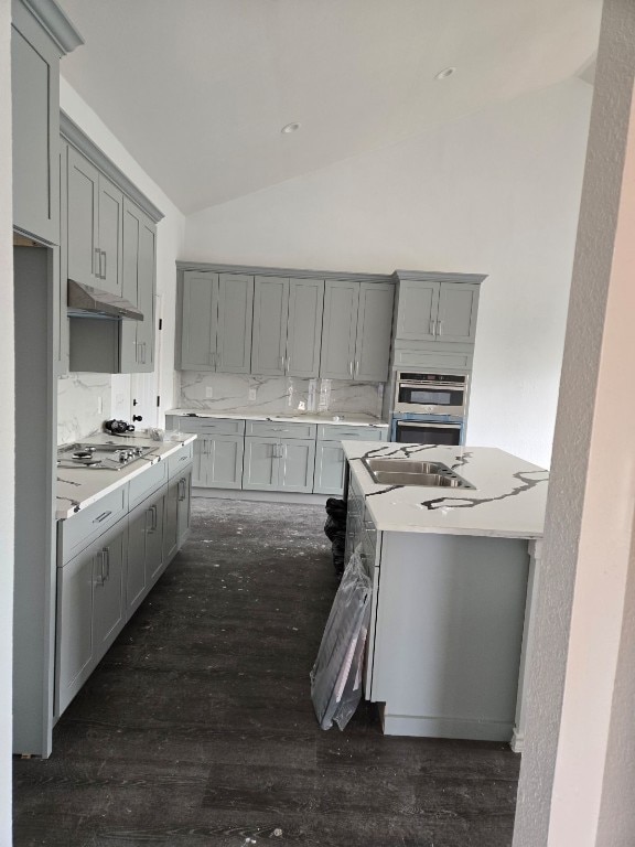 1525 Waco St, Gonzales, TX 78629 - kitchen featuring gray cabinetry, under cabinet range hood, a sink, vaulted ceiling, and dark wood finished floors