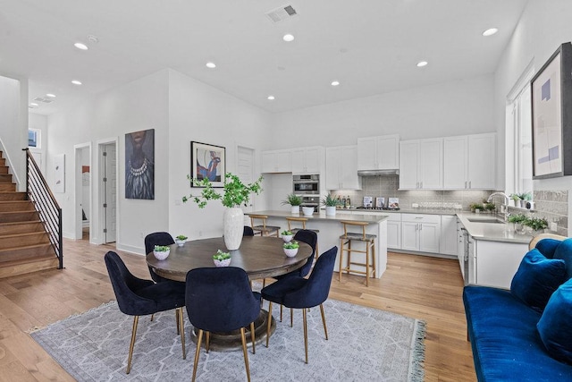 5324 Agatha Cir, Austin, TX 78724 - dining space featuring recessed lighting, stairs, light wood-type flooring, and a towering ceiling