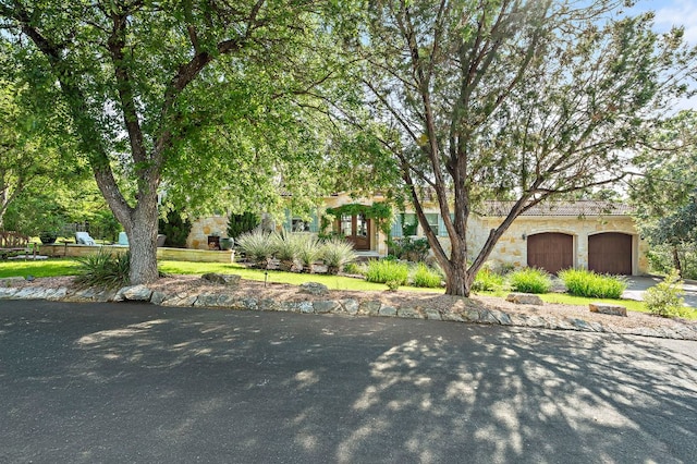 1607 The High Rd, Austin, TX 78746 - view of property hidden behind natural elements featuring concrete driveway, stone siding, and a garage