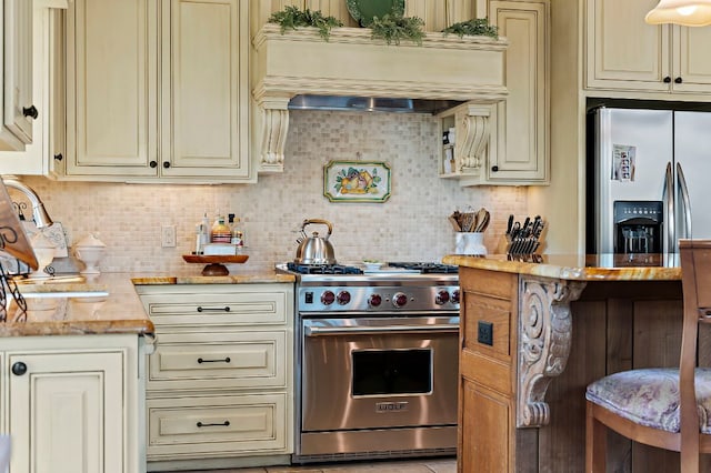 1607 The High Rd, Austin, TX 78746 - kitchen with cream cabinets, stainless steel appliances, light stone countertops, and tasteful backsplash
