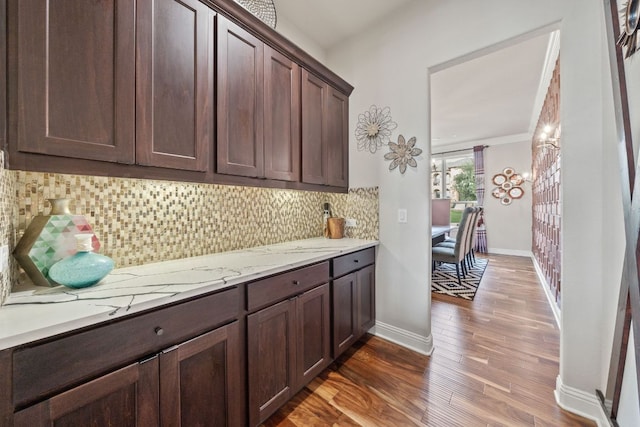 2329 Sandorna Ct, Leander, TX 78641 - kitchen featuring wood finished floors, dark brown cabinetry, backsplash, and light stone counters