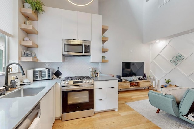913 Duncan Ln Unit 103, Austin, TX 78705 - kitchen with open shelves, stainless steel appliances, a sink, light wood finished floors, and open floor plan