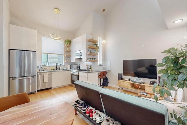 913 Duncan Ln Unit 103, Austin, TX 78705 - kitchen with appliances with stainless steel finishes, vaulted ceiling, open shelves, light wood-style flooring, and white cabinets