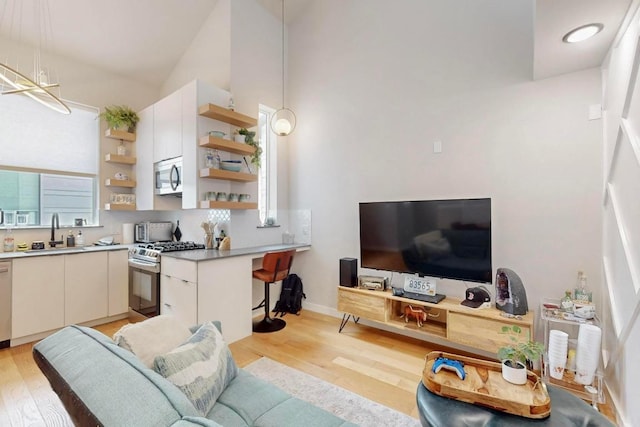 913 Duncan Ln Unit 103, Austin, TX 78705 - kitchen featuring stainless steel appliances, open shelves, a sink, light wood-style floors, and white cabinets