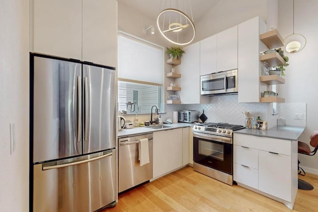 913 Duncan Ln Unit 103, Austin, TX 78705 - kitchen featuring open shelves, appliances with stainless steel finishes, a sink, light wood-type flooring, and decorative backsplash