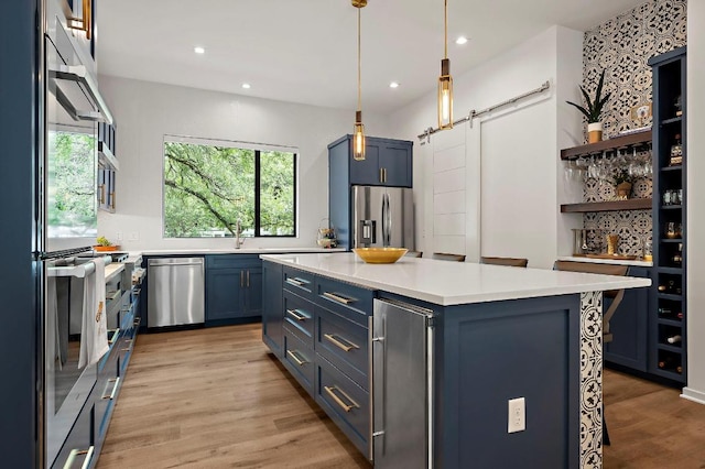 2312 Pruett St, Austin, TX 78703 - kitchen with appliances with stainless steel finishes, blue cabinetry, light countertops, light wood-type flooring, and a barn door