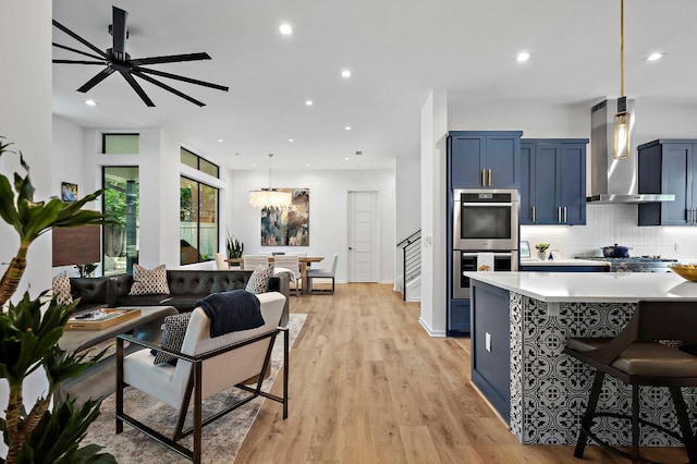 2312 Pruett St, Austin, TX 78703 - kitchen with wall chimney range hood, appliances with stainless steel finishes, blue cabinets, tasteful backsplash, and a kitchen breakfast bar