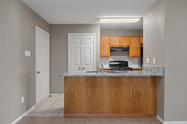 11814 Barrington Way, Austin, TX 78759 - kitchen with stove, a sink, under cabinet range hood, brown cabinets, and baseboards