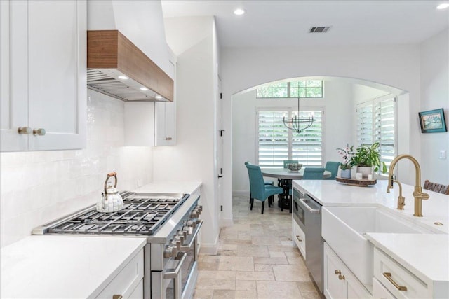 213 Black Wolf Run, Austin, TX 78738 - kitchen with custom range hood, appliances with stainless steel finishes, arched walkways, backsplash, and a chandelier