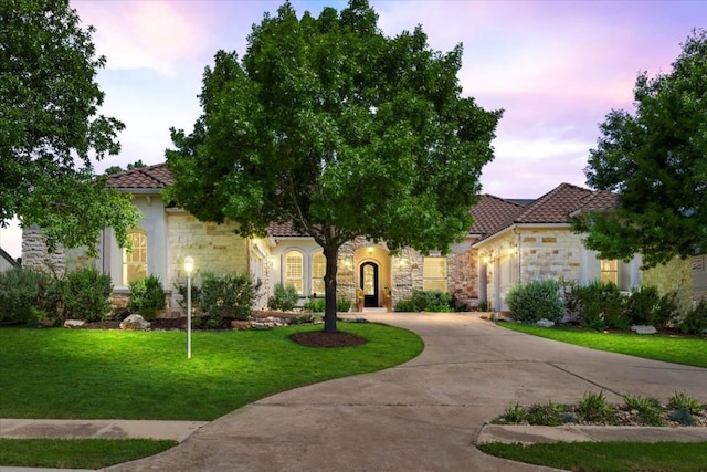 213 Black Wolf Run, Austin, TX 78738 - mediterranean / spanish house with stone siding, concrete driveway, a front yard, and a tiled roof