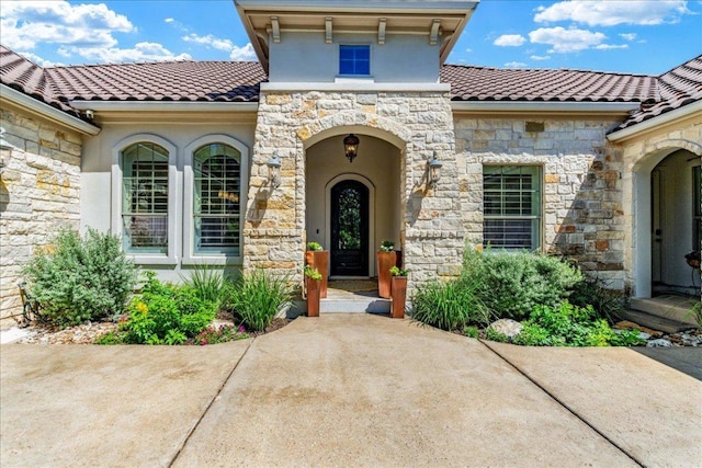213 Black Wolf Run, Austin, TX 78738 - property entrance with stone siding, stucco siding, and a tiled roof