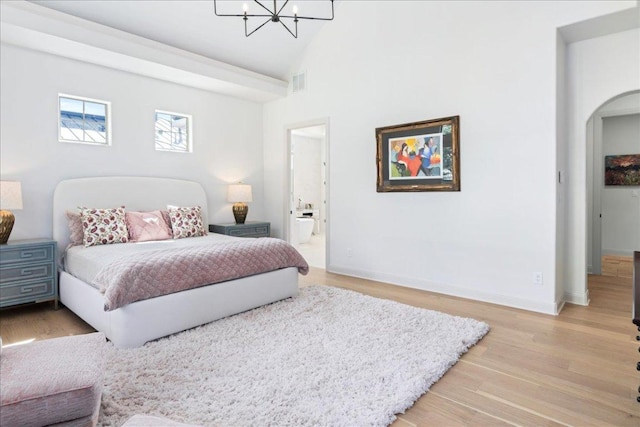 213 Black Wolf Run, Austin, TX 78738 - bedroom with a chandelier, arched walkways, light wood-type flooring, baseboards, and high vaulted ceiling