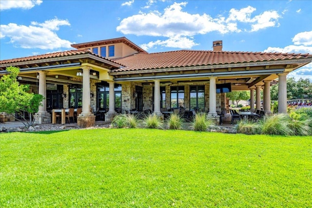 213 Black Wolf Run, Austin, TX 78738 - back of house featuring a yard, a chimney, a tiled roof, and stone siding