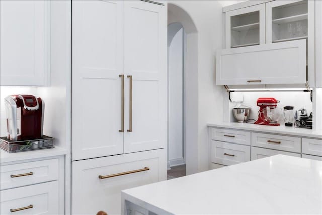 213 Black Wolf Run, Austin, TX 78738 - kitchen with white cabinetry, light countertops, glass insert cabinets, and arched walkways