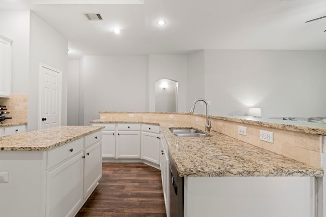 6307 Clairmont Dr, Austin, TX 78749 - kitchen with a sink, a kitchen island with sink, dark wood-type flooring, tasteful backsplash, and arched walkways