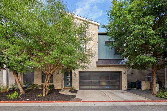 2807 Del Curto Rd Unit G, Austin, TX 78704 - view of front of property featuring an attached garage, a standing seam roof, driveway, stone siding, and metal roof