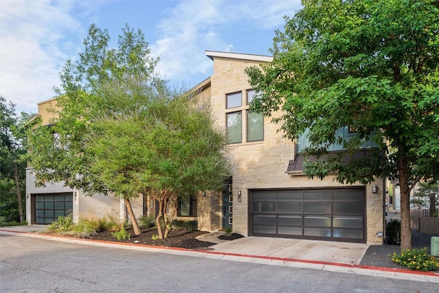 2807 Del Curto Rd Unit G, Austin, TX 78704 - view of front of house featuring stone siding, a garage, and concrete driveway