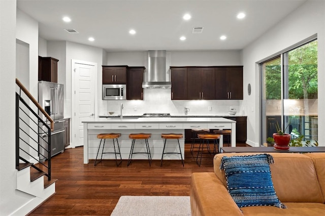 2807 Del Curto Rd Unit G, Austin, TX 78704 - kitchen featuring wall chimney range hood, appliances with stainless steel finishes, a sink, a kitchen island with sink, and dark wood finished floors