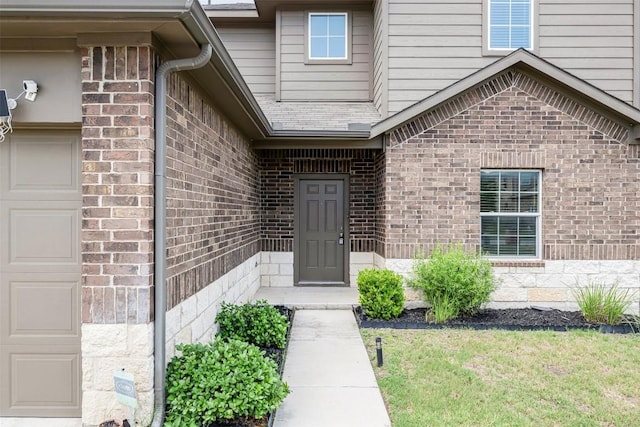 10820 Gonzales Ranger Pass, Austin, TX 78754 - view of exterior entry featuring brick siding, a garage, and a yard