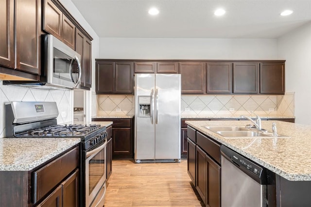 10820 Gonzales Ranger Pass, Austin, TX 78754 - kitchen featuring stainless steel appliances, a sink, dark brown cabinetry, light wood-style floors, and recessed lighting