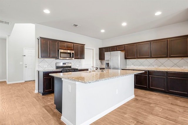 10820 Gonzales Ranger Pass, Austin, TX 78754 - kitchen with appliances with stainless steel finishes, a sink, backsplash, dark brown cabinets, and light wood-type flooring