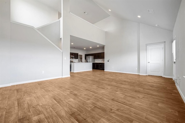 10820 Gonzales Ranger Pass, Austin, TX 78754 - unfurnished living room featuring high vaulted ceiling, baseboards, light wood finished floors, and recessed lighting