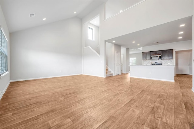 10820 Gonzales Ranger Pass, Austin, TX 78754 - unfurnished living room featuring high vaulted ceiling, stairs, light wood-type flooring, recessed lighting, and baseboards